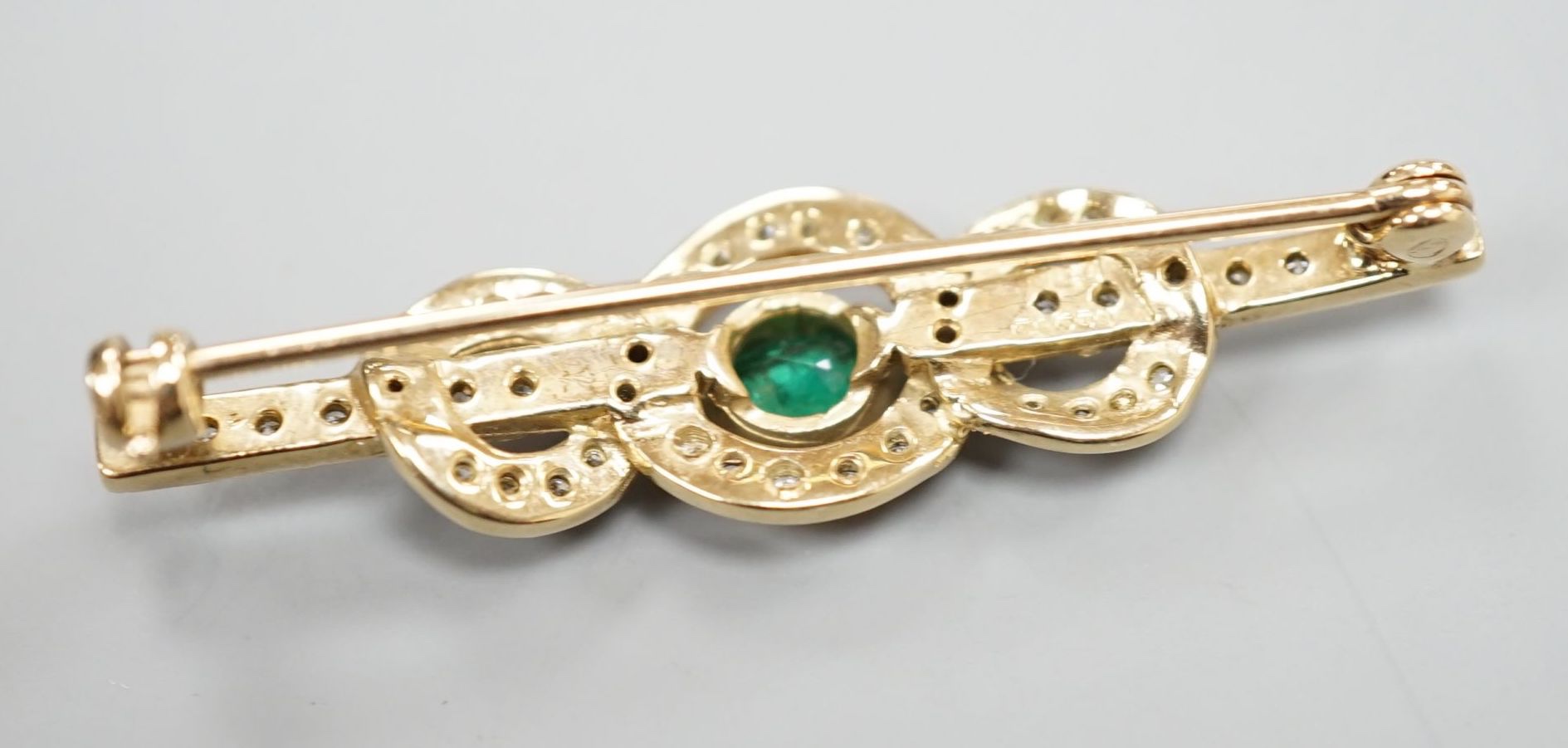 A modern 9ct gold, emerald and diamond cluster set bar brooch, 43mm, gross 3.9 grams.